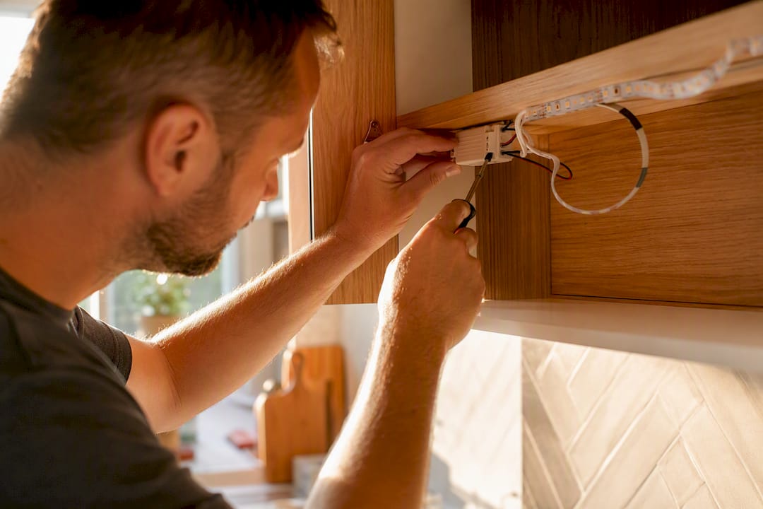 Hands repairing LED light wiring under cabinet